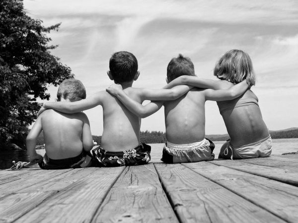 Девочка и три мальчика сидят на берегу